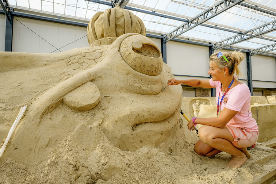 Künstlerin bearbeitet Sandskulptur für die Ausstellung 2021 in Prora auf der Insel Rügen